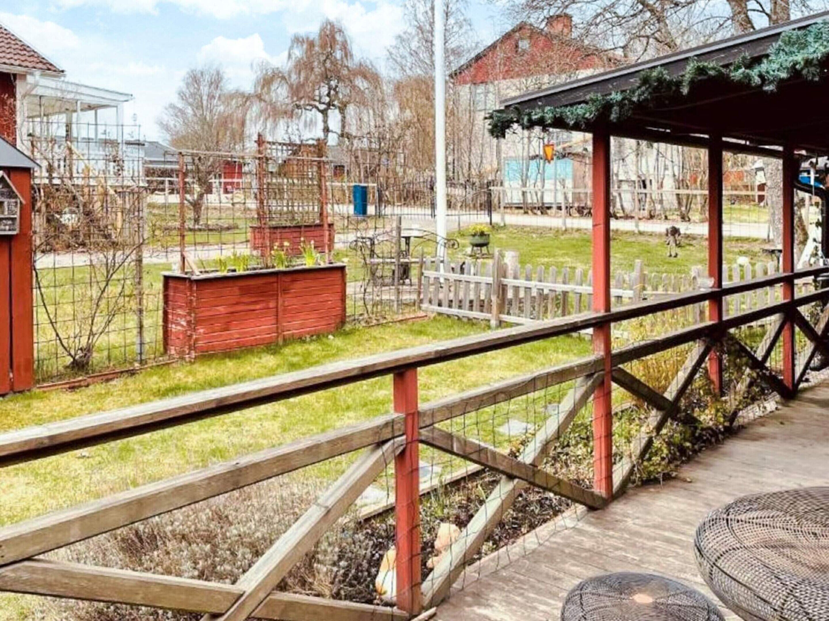 A wooden deck with a metal railing, a covered seating area, and a fenced garden with a small shed.