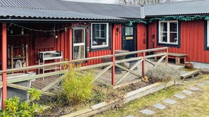 A red building with a metal roof, a wooden deck, and a small outdoor seating area. - 6 Person Holiday Home in Kosta (Kosta)