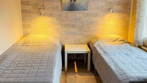A room with two single beds, a small white nightstand, a painting on the wall, and a window with curtains. - 6 Person Holiday Home in Kosta (Kosta)