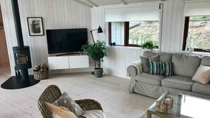 A cozy living room with a sofa, a television, a fireplace, and a view of the outdoors. - 4 Star Holiday Home in Ebeltoft (Ebeltoft)