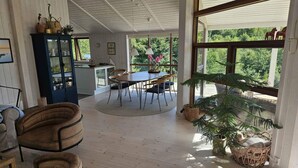 A spacious room with a dining area, a large window, and a view of greenery. - 4 Star Holiday Home in Ebeltoft (Ebeltoft)