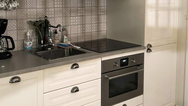 Una cocina con estufa negra, horno de acero inoxidable y un lavamanos con grifo.