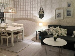 Un salon comprenant une table à manger, un canapé, une table basse ronde, une lampe et des tableaux encadrés accrochés au mur.