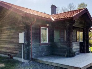 Une cabane en bois avec une véranda, une cheminée et une fenêtre.