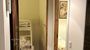 Un pasillo estrecho que conduce a una habitación con literas y una puerta de madera.