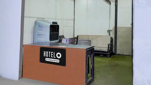 A hotel reception desk with a sign indicating it is company-serviced. There is a chair and a fan in the background. - Saver Double Bella's Residency (Calangute)