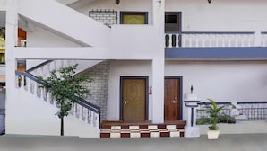 A two-story building with a staircase, a wooden door, and a potted plant. - Saver Double Bella's Residency (Calangute)