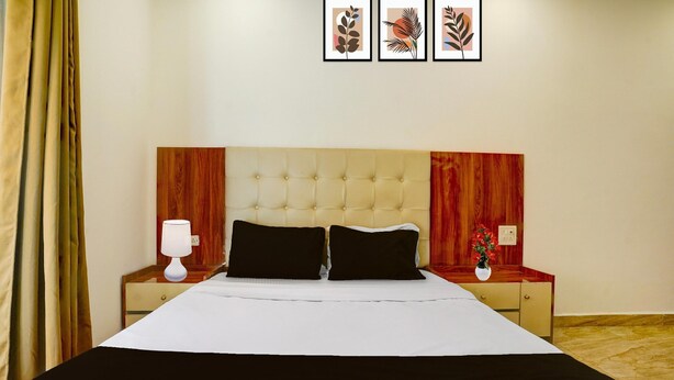 A hotel room with a large bed, two bedside tables, a nightstand, a lamp, and framed artwork on the wall. - Saver Double Bella's Residency (Calangute)