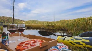 Un tavolo da pranzo con una scatola per pizza, bicchieri da vino e un kayak.