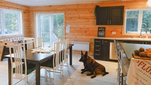 Un interno in legno con zona pranzo, cucina e un cane seduto sul pavimento.