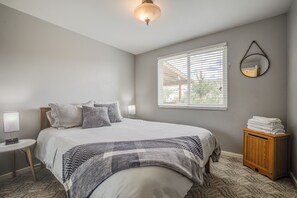 A bedroom with a bed, bedside table, lamp, window with blinds, and a mirror on the wall. - 4 Bedroom home with patio overlooking Wind River (Dubois)