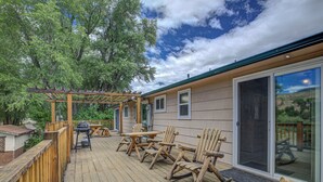 A wooden deck with outdoor furniture, a pergola, and a sliding glass door.