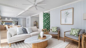 A modern living room with a sofa, chairs, a coffee table, and a ceiling fan. - Coastal Waterfront Broadbeach Waters (Broadbeach Waters)
