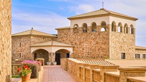 A stone building with arches, a tiled roof, and a pathway leading to a gated entrance. - Apartment Inmas Nou With Shared Pool (Castell-Platja d'Aro)