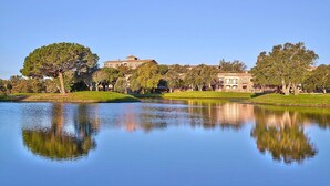 A serene lake with a reflection of trees and buildings, surrounded by well-maintained lawns and a clear sky. - Apartment Inmas Nou With Shared Pool (Castell-Platja d'Aro)