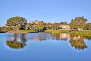 A serene lake with a reflection of trees and buildings, surrounded by well-maintained lawns and a clear sky. - Apartment Inmas Nou With Shared Pool (Castell-Platja d'Aro)