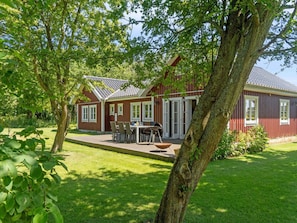 A red wooden house with a patio, a barbecue, and a lawn. - 4 Star Holiday Home in Dannemare (Dannemare)