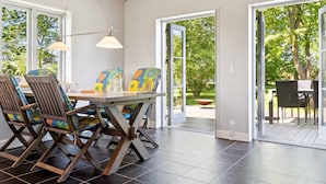 A dining area with a table and chairs, large windows, and a view of the outdoors. - 4 Star Holiday Home in Dannemare (Dannemare)