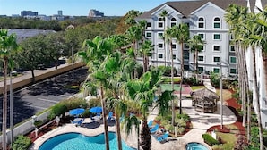 A hotel with a swimming pool, palm trees, and a view of the city. - Relaxing and charming 1Bd/1Bh Retreat  - FREE Shuttle (Orlando)