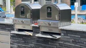 Two outdoor barbecue grills with digital displays, a poolside area with lounge chairs, and a brick wall. - Relaxing and charming 1Bd/1Bh Retreat  - FREE Shuttle (Orlando)
