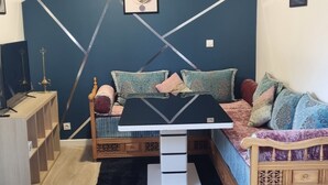 Une pièce comprenant un lit, un bureau et une chaise. Un mur est décoré d’un motif géométrique et un tableau y est accroché.