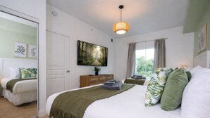 Een slaapkamer met een bed, een dressoir, een spiegel, een schilderij en een raam.