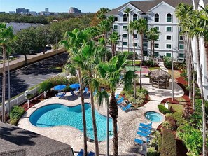 A hotel with a swimming pool, palm trees, and a view of the city. - Inspiring and cozy Botanic Retreat - FREE Shuttle (Orlando)