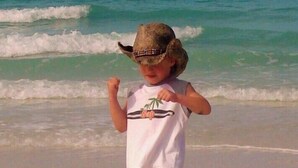 Un niño en la playa con olas al fondo.