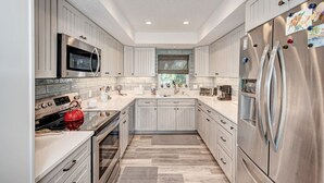 Una cocina moderna con muebles blancos, electrodomésticos de acero inoxidable y salpicadero de azulejos.