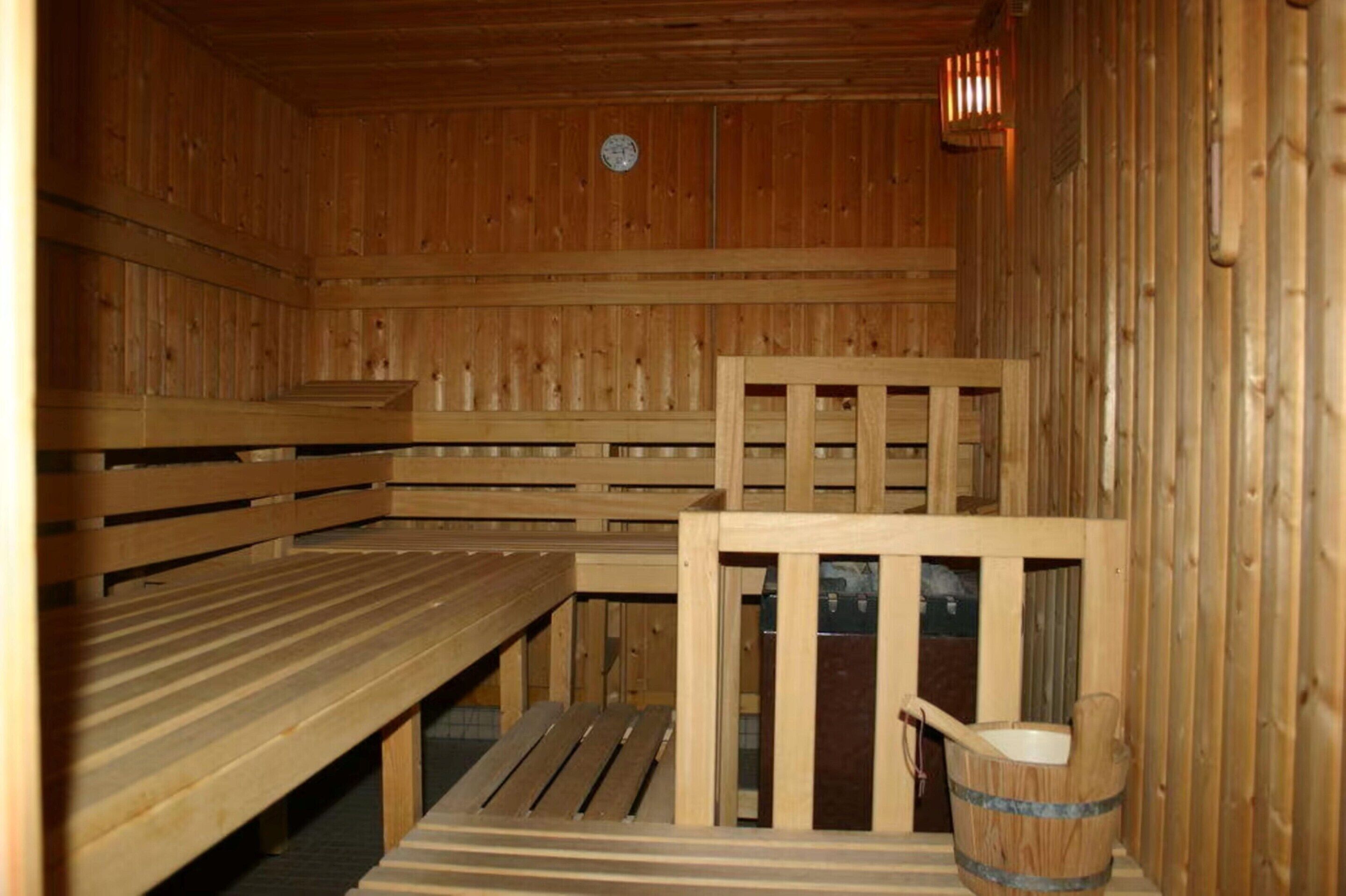 Een houten sauna met banken en een houten emmer.