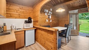 L’intérieur d’un chalet en bois comprend une cuisine, un coin repas et une porte donnant sur un jardin.