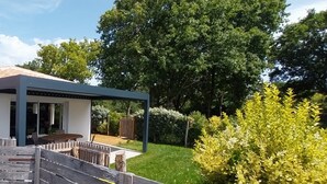 Uma casa moderna com um alpendre coberto, uma porta e um jardim.