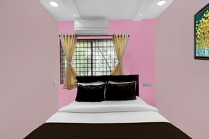 Une chambre à coucher avec un lit, un appareil de climatisation, une fenêtre avec des rideaux et un tableau au mur.