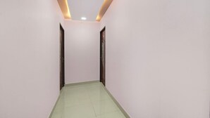 Um corredor com paredes brancas, chão verde e iluminação embutida.