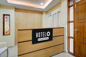 Un comptoir d’accueil avec une pancarte indiquant « HOTELO, services d’entreprise ».