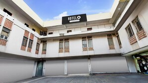 Um hotel com uma placa indicando 'HOTELO Company Serviced', janelas amplas e persianas fechadas.