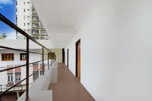 A corridor with a metal railing, white walls, and a view of adjacent buildings. - Deluxe Hotel Birla Stay Inn (Hyderabad)