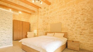 A bedroom with a stone wall, wooden bed frame, and a nightstand.