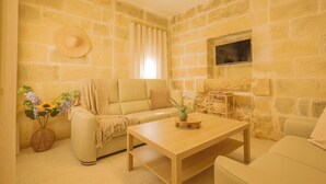 A cozy living room with a beige sofa, a wooden coffee table, and a stone wall.