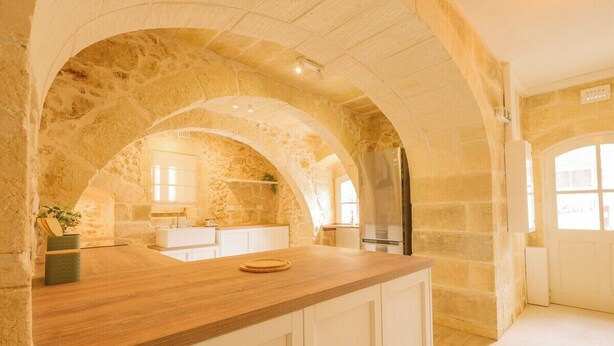 A kitchen with stone arches, a wooden countertop, and a stainless steel refrigerator.