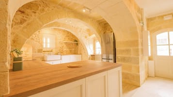 A kitchen with stone arches, a wooden countertop, and a stainless steel refrigerator.