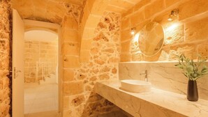 A stone-walled bathroom with a marble sink and a mirror.