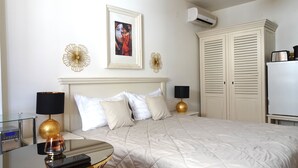 Una camera d'albergo con un letto, abat-jour, un quadro incorniciato, un condizionatore d'aria e un armadio.