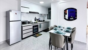 Una cocina moderna con comedor, armarios blancos y un espejo grande.