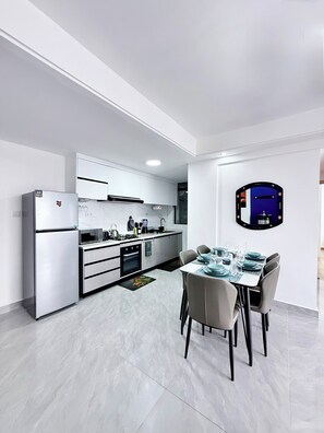 A modern kitchen with a dining area, white cabinetry, and a large mirror. - Araka Homes-Westlands/Elegant 2 Bedroom Apartment (Nairobi)