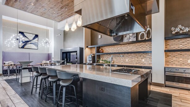 Una cocina moderna con una isla central, taburetes de bar y un comedor con sofá y mesa.