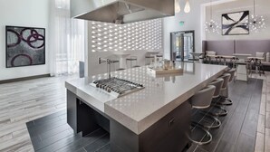 Una cocina moderna con una isla central, taburetes de bar y una zona de estar con sofá y mesa.