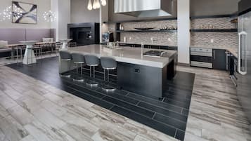 Een moderne keuken met een groot eiland, barstoelen, een ingebouwde oven en een spatwand met een geruit patroon.