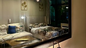 Ein Schlafzimmer mit einem Bett, einem Schlafsofa, einem Spiegel und einem Nachttisch.