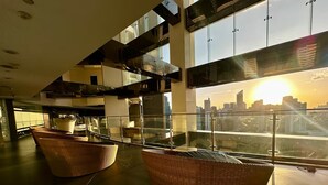 Ein modernes Interieur mit Korbmöbeln, Blick auf die Stadtlandschaft und hohen Decken.